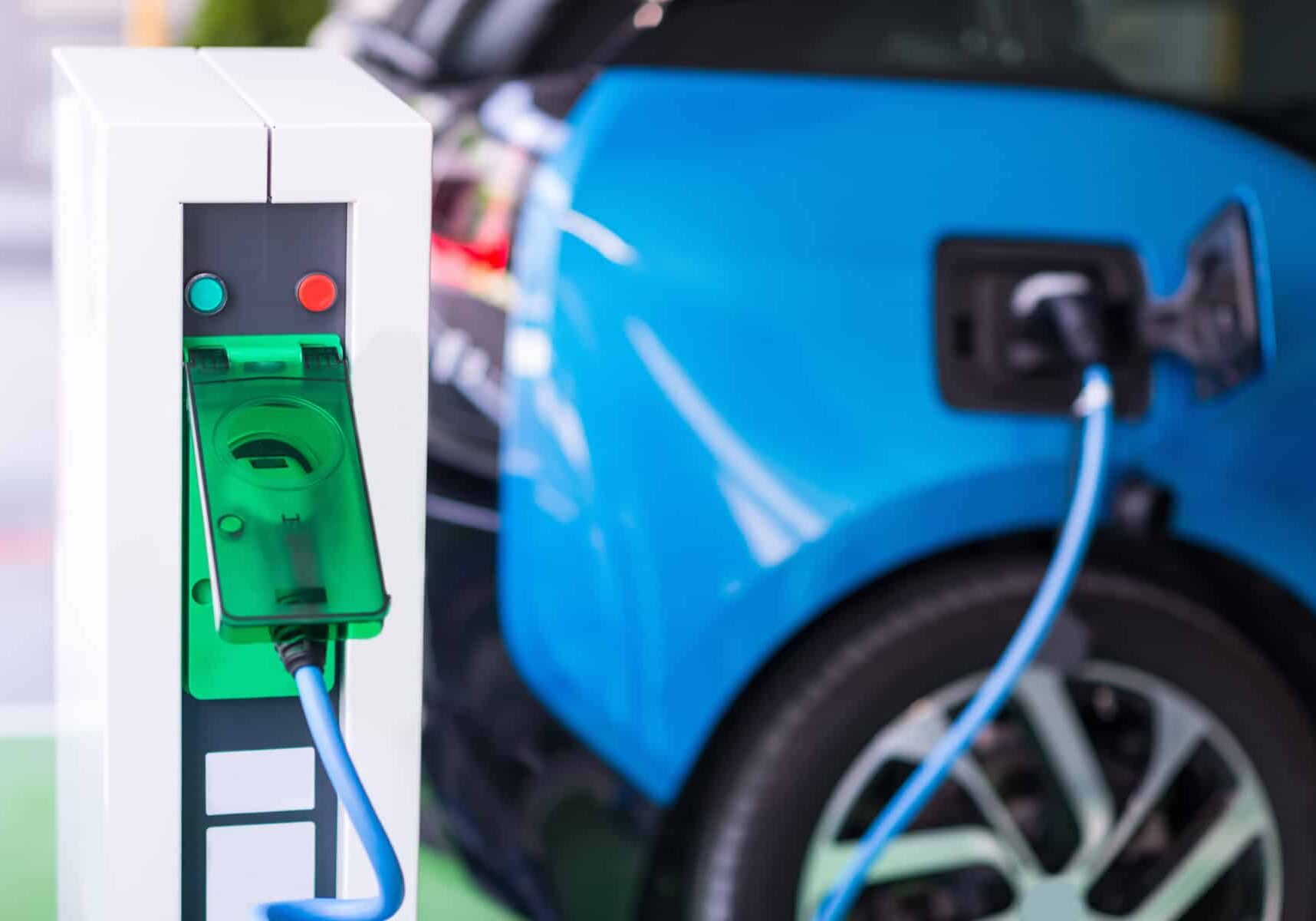A blue car is plugged into an electric charging station.